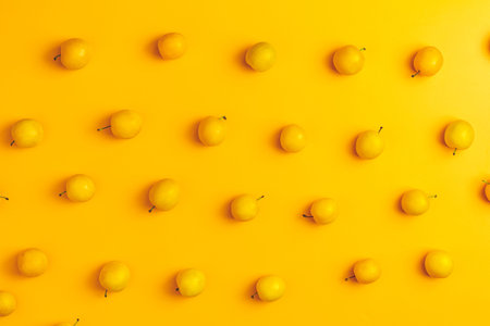 Creative summer pattern made of fresh yellow cherry plums on pastel yellow background. Fruit minimal...