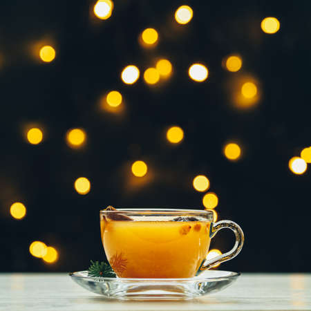 Cup of hot spicy tea with yellow orange with light bokeh. Beautiful holiday drink concept with copy spaceの写真素材