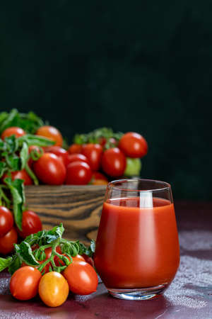 Glass of fresh delicious jummy red tomato juice and fresh tomatoes in wooden box. Dark background. Close up. Gmo free. Natural good foodの写真素材