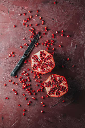 Fresh juicy pomegranate - whole and cut on a dark claret concrete vintage background, top view, horizontal, with copy spaceの写真素材
