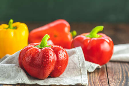 Ripe organic fresh sweet red and yellow pepper on dark wooden table. Selection of healthy food for heart, life conceptの写真素材