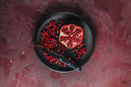 Fresh juicy pomegranate - whole and cut on a dark claret concrete vintage background, top view, horizontal, with copy spaceの写真素材