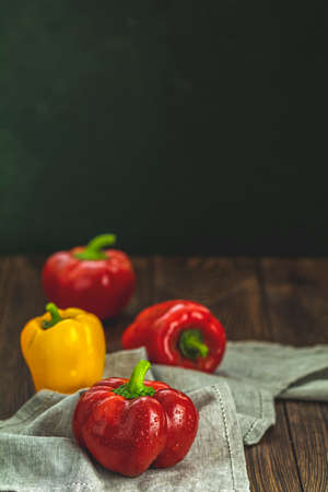 Ripe organic fresh sweet red and yellow pepper on dark wooden table. Selection of healthy food for heart, life conceptの写真素材