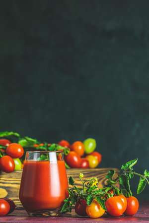 Glass of fresh delicious jummy red tomato juice and fresh tomatoes in wooden box. Dark background. Close up. Gmo free. Natural good foodの写真素材
