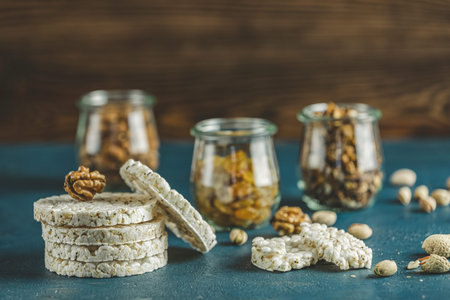 Stack of rice cakes. American puffed rice cakes. Healthy snacks with almonds, raisins, peanuts,...