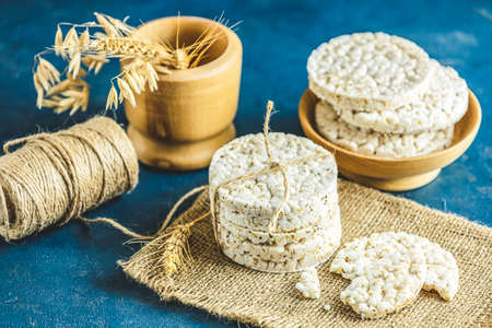 Stack of rice cakes. American puffed rice cakes. Healthy snacks with ears of wheat on classic blue concrete surface. Close up.の写真素材