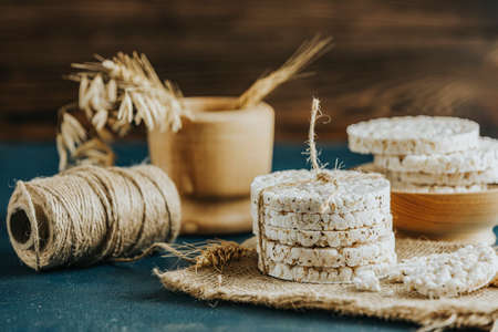 Stack of rice cakes. American puffed rice cakes. Healthy snacks with ears of wheat on classic blue concrete surface. Color of 2020 year. Classic Blue.の写真素材