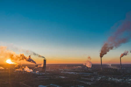 Drone fly AERIAL: industrial plant. Air pollution from industrial plants. Pipes throwing smoke in the sky at sunset. Sunset in the sky above the industrial area.の写真素材