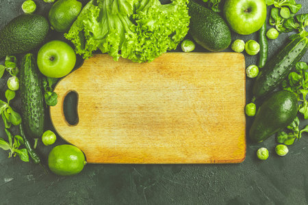 Fresh organic green vegetables and fruits on green background. Spring diet, healthy raw vegetarian,...