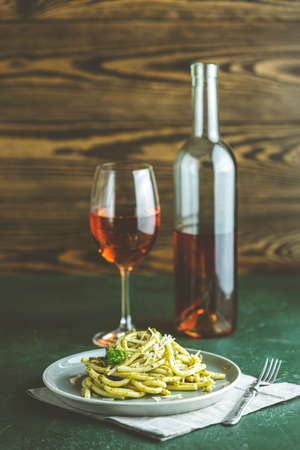 Spaghetti pasta bucatini with pesto sauce and parmesan. Italian traditional perciatelli pasta by genovese pesto sauce in gray dish served with wine	の写真素材