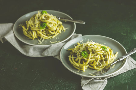 Spaghetti pasta bucatini with pesto sauce and parmesan. Italian traditional perciatelli pasta by genovese pesto sauce in two gray dishes	の写真素材