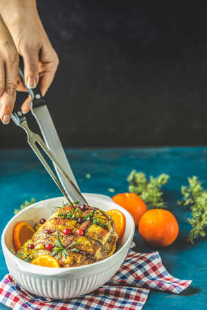 Color of 2020 year. Classic Blue, food trendy background. Roasted pork in white dish, christmas baked ham with cranberries, tangerines, thyme, rosemary, garlic on dark table surfaceの写真素材