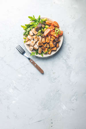 Healthy food. Plate of baking chicken meat, fried sweet potato and brussels sprouts. Top view, light gray concrete surface, flat lay.の写真素材