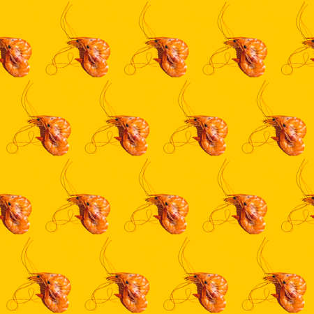 Food diagonal seamless pattern of shrimps on bright yellow background. Creative minimalist flat lay with hard light.の写真素材