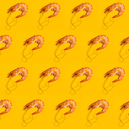 Food diagonal seamless pattern of shrimps on bright yellow background. Creative minimalist flat lay with hard light.の写真素材