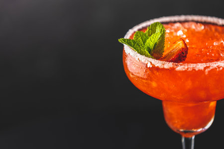 Fragment of frozen strawberry lime mint margarita in tall footed glass on the dark background close up. Luxury alcohol freshの写真素材