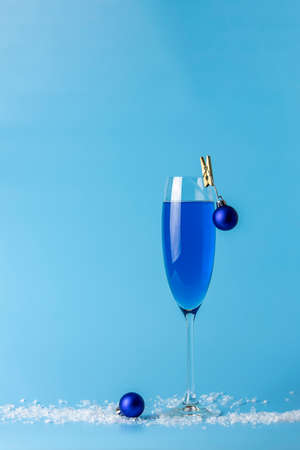 Wineglass of blue champagne  on a blue background with Christmas an New Year decor. Shallow depth of the field, copy space for you text.の写真素材