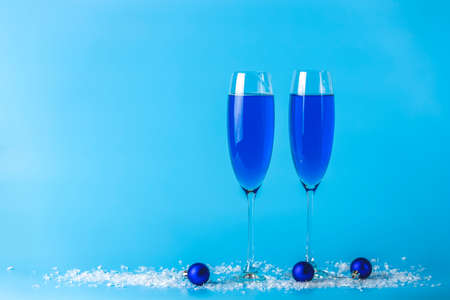 Two wineglasses of blue champagne  on a blue background with Christmas an New Year decor. Shallow depth of the field, copy space for you text.の写真素材