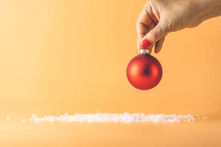 Woman hand support Christmas ball. Christmas background with red ball on yellow. Merry christmas greeting card. Winter holiday xmas theme. Happy New Year. Space for textの写真素材