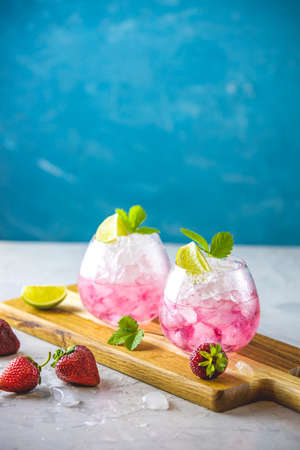 Pink cocktail with lime, crushed ice, strawberries and mint on the light background, selective focus image, copy spice for you text, summer vacation and party concept.の写真素材