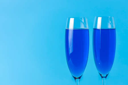 Two wineglasses close up of blue champagne on a blue background. Shallow depth of the field, copy space for you text.の写真素材