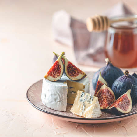 Blue or bleu cheese with fig and honey or maple syrup on pink plate. Tasty white cheese close up view.の写真素材
