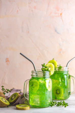Glass jar of kiwi juice or smoothie. Kiwi Mojito cocktail or non-alcohol mocktail with mint and sliced kiwi fruits on wooden background copy spaceの写真素材