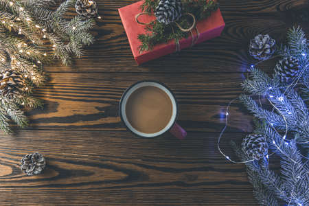 Christmas background with cup of cocoa and gift box wrapped in holiday paper over dark wooden table prepared for celebrating festive holiday season. Copy space.の写真素材