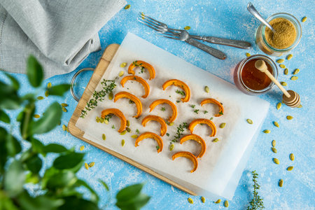 Autumn vegetarian food recipe. Baked mini pumpkin with  herbs, and honey on a wooden board over light blue table top view.の写真素材