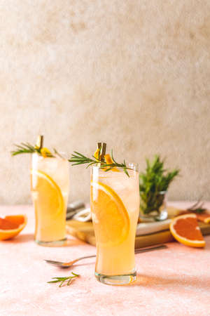 Two glasses of Paloma cocktails with tequila fresh grapefruit juice combined and rosemary. Light pink concrete surface.の写真素材