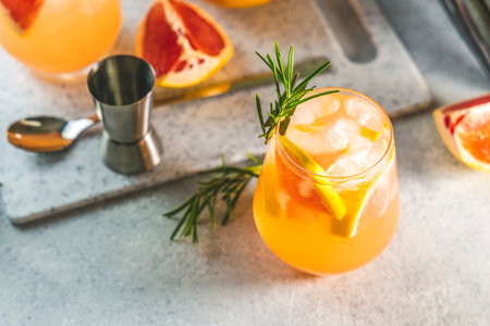 Two glasses of cold lemonade of fresh grapefruit juice, alcohol and ice cubes decorated slice citrus and twig rosemary, light gray concrete  surface.の写真素材