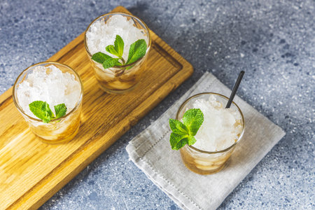 Mint Julep cocktail with bourbon, ice and mint in glass on light gray table surface. Close up,...