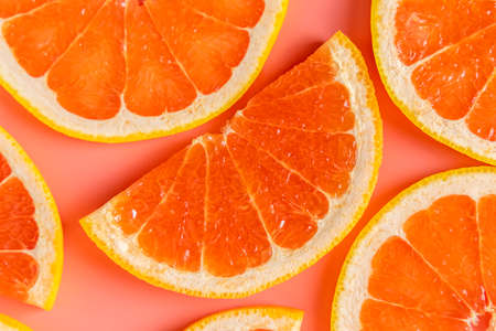 Group of fresh organic grapefruit slices over pink background. Flat lay, spaceの写真素材