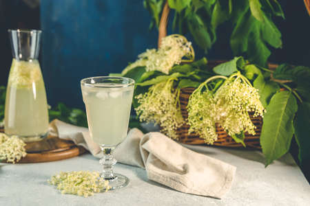 Soft drink with ice cubes from elderflower syrup, juice or champagne in a glass on a light gray table surface, selected focus, narrow depth of fieldの写真素材