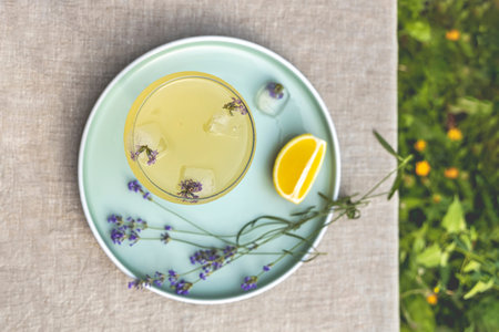 Top view Pompadour glass of lavender lemonade with cube ice with lavender flowers. Table in summer...