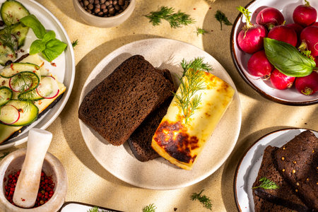 Delicious baked cheese is served with rye bread and fresh vegetables for a healthy lunch