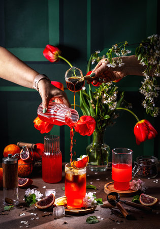 Two people are making a refreshing summer cocktail with coffee, orange, ice, and flowers