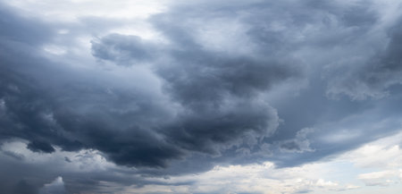 Ominous dark storm clouds are gathering in the sky, creating a dramatic and moody scene, hinting at an impending downpourの写真素材