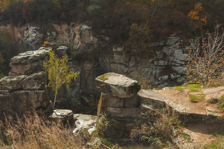 Moss covered rocks and vibrant trees create a breathtaking autumn landscape within an old stone quarry, showcasing nature's colorful beautyの写真素材