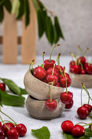 Ripe, juicy cherries spilling from stacked ceramic bowls, creating a vibrant display of freshnessの写真素材
