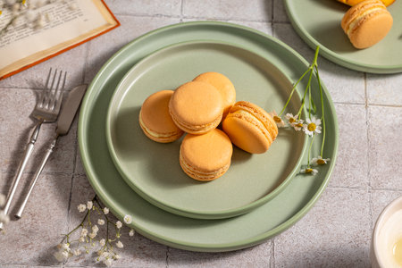 Vibrant orange macarons are beautifully arranged on elegant green plates, creating a visually appealing scene that suggests a delightful culinary experienceの写真素材