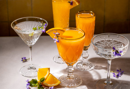 Crystal glasses filled with vibrant orange juice, garnished with orange slices and delicate violet flowers, create a sophisticated and refreshing sceneの写真素材