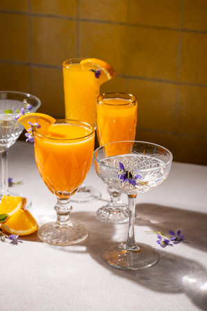 Elegant glasses filled with vibrant orange cocktails, garnished with edible flowers and orange slices, create a refreshing and visually appealing sceneの写真素材