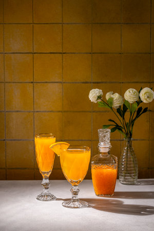 Refreshing orange juice served in elegant glasses, accompanied by a decorative carafe and a vase of white flowers, creating a vibrant and inviting sceneの写真素材