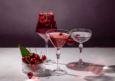 Elegant glassware containing cherry cocktails and a bowl of fresh cherries create a vibrant and...