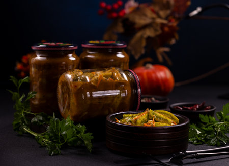 Pickled vegetables in glass jars with a small bowl on a dark table, rustic homemade canning from autumn harvest ready to eatpreserved, seasonal, healthy comfort food for winterの写真素材