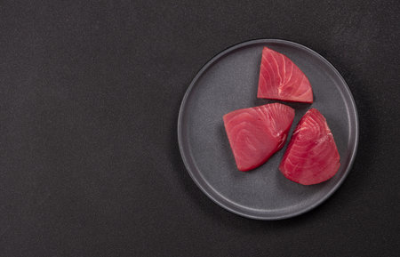 Fresh red tuna portions arranged on a dark background ready for cooking or sashimi, highlighting lean protein, omega 3 rich seafood and gourmet culinary preparationの写真素材
