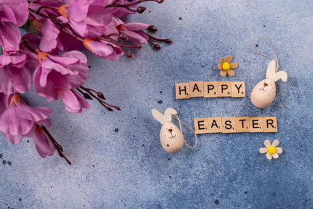 Easter greeting spelled with wooden letter tiles surrounded by bunny shaped speckled eggs, felt...