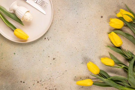 Festive spring table with a speckled easter egg in a ceramic egg cup on a plate, cutlery and a...