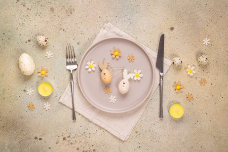 Easter table setting showing decorated plate with wooden bunny eggs, cutlery, candles, and...